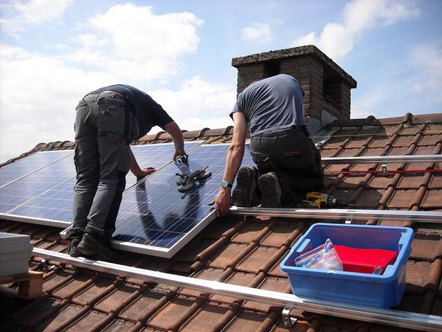 Homem instalando painel solar em telhado residencial