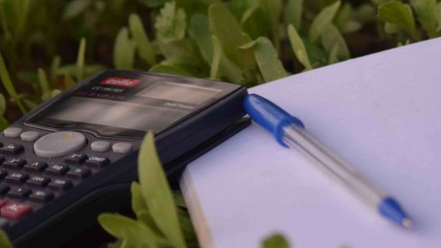 bloco de notas e uma caneta sobre a grama