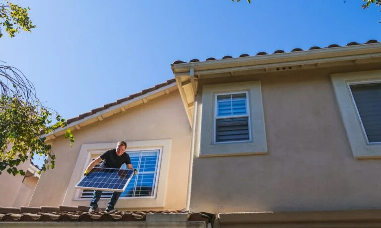 homem com painél solar em cima do telhado de uma casa