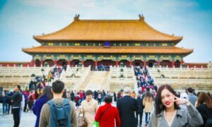 Templo com pessoas visitando e mulher posando para foto